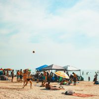 An iconic Canadian beach summer scene — golden skies, warm sand, and a shoreline alive with sunset energy.