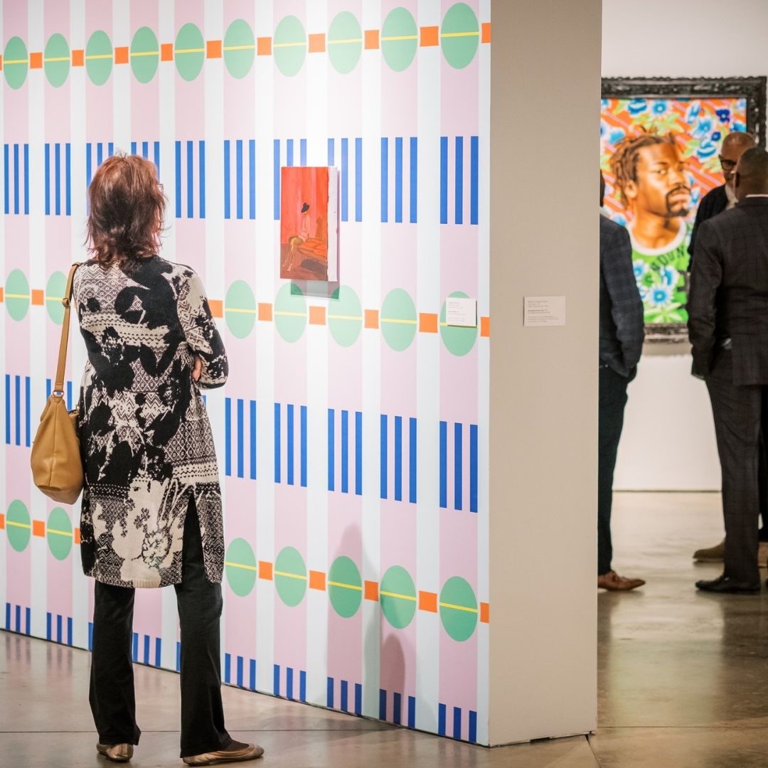 A patron observes an artwork by Danielle McKinney installed against Merryn Omotayo Alaka's vinyl wallpaper on view 
