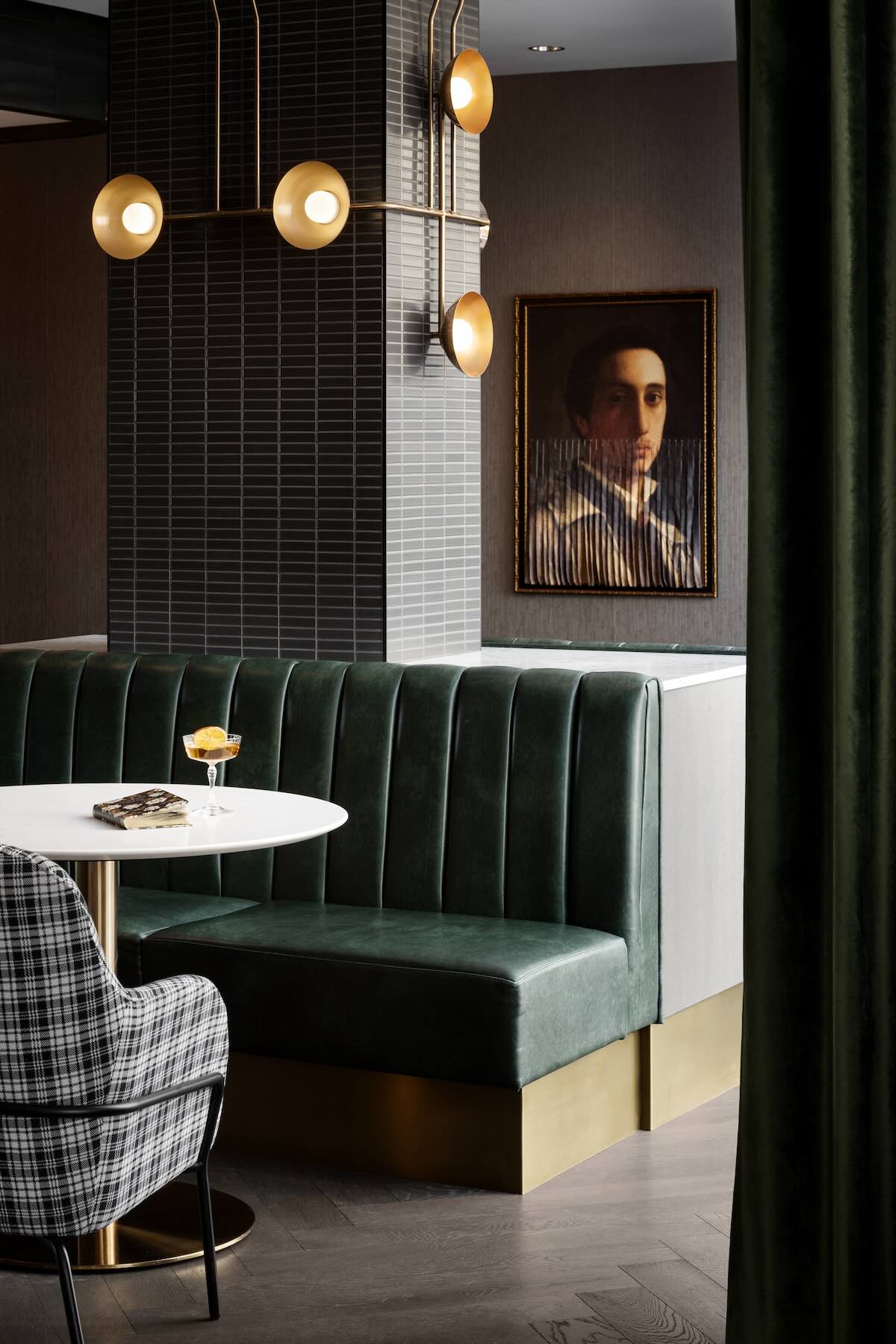 A-close-up-of-restaurant-with-dark-green-sofa-and-image-of-man-on-wall-as-art