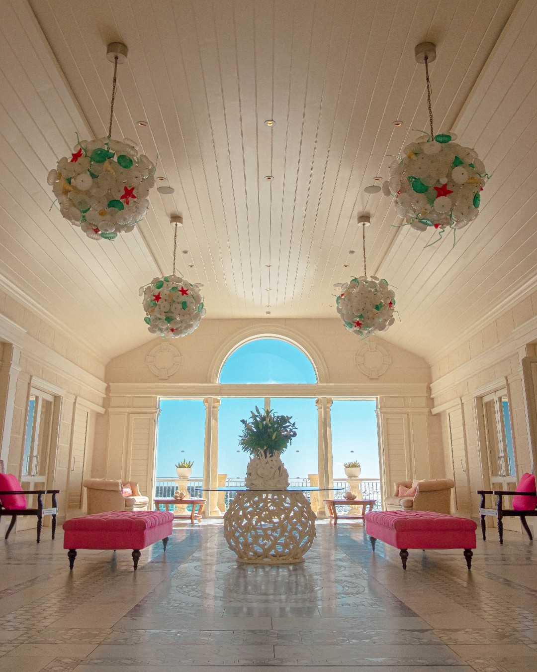 Mandarin Oriental Canouan’s lobby with cool marble floors, soft cream tones, sparkling chandeliers, and natural light highlighting the island’s beauty.