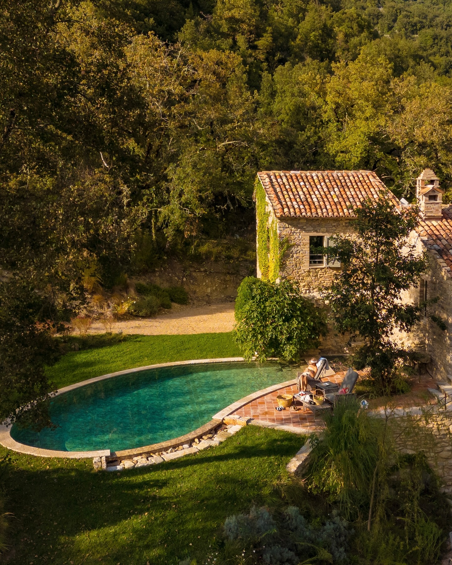 Exterior view of Villa Molinella, a stone villa with terracotta roof, private pool, outdoor seating, and greenery nestled in the Umbrian hills.