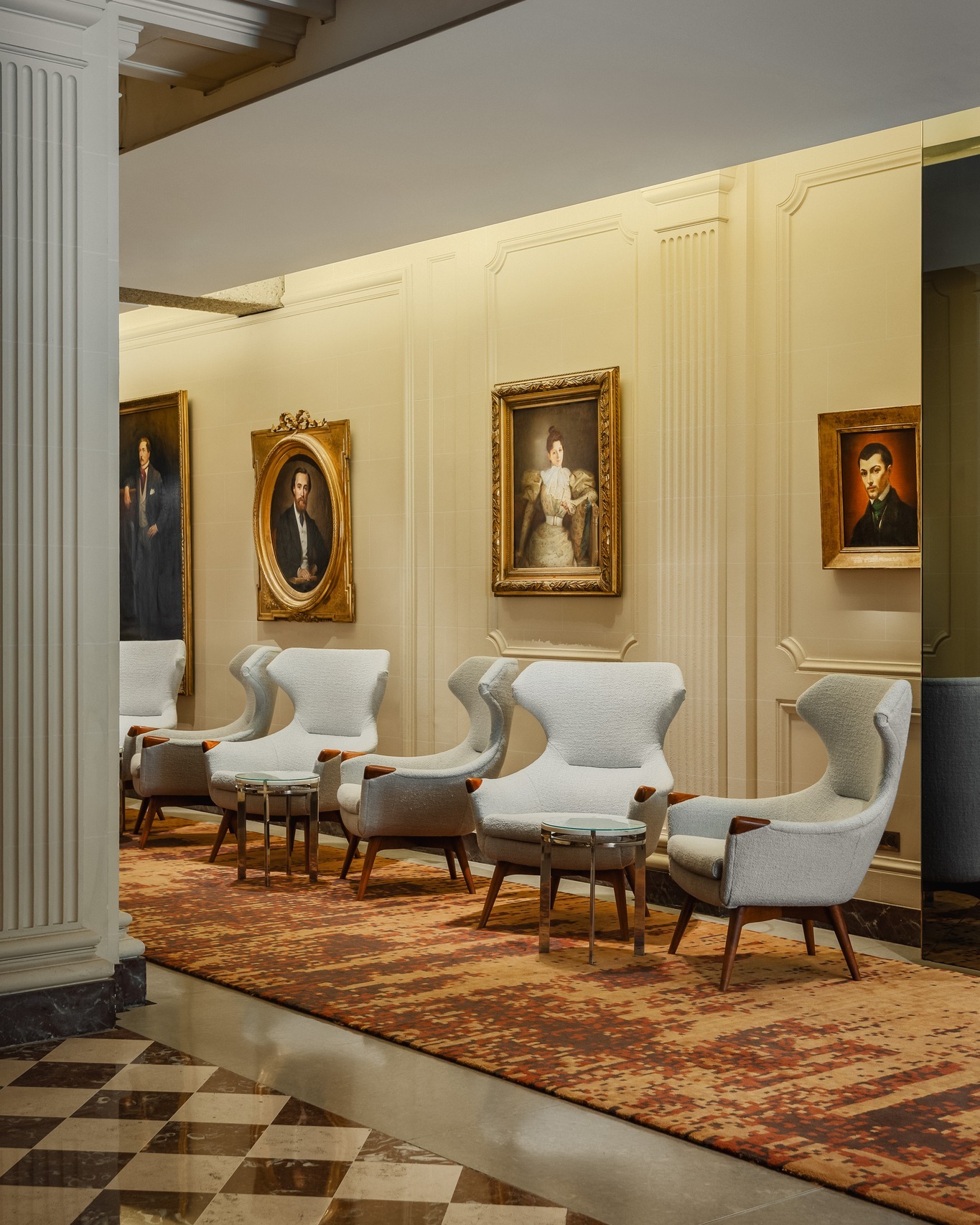 Portrait gallery at Hotel de Sers showcasing historic artwork and contemporary lounge chairs.