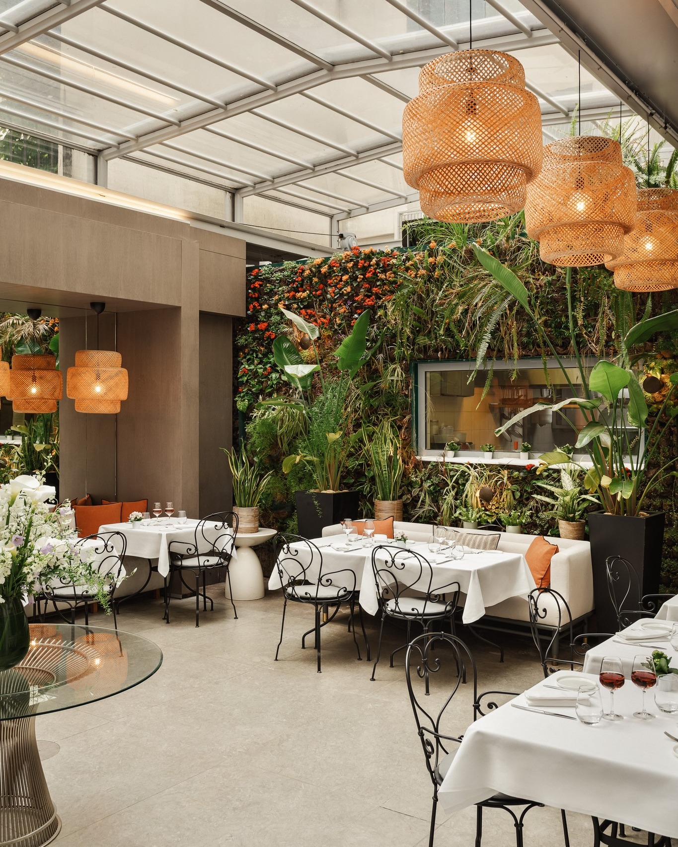 Luxury courtyard dining at Hotel de Sers in Paris, featuring a glass canopy, lush vertical garden, and elegant table settings.