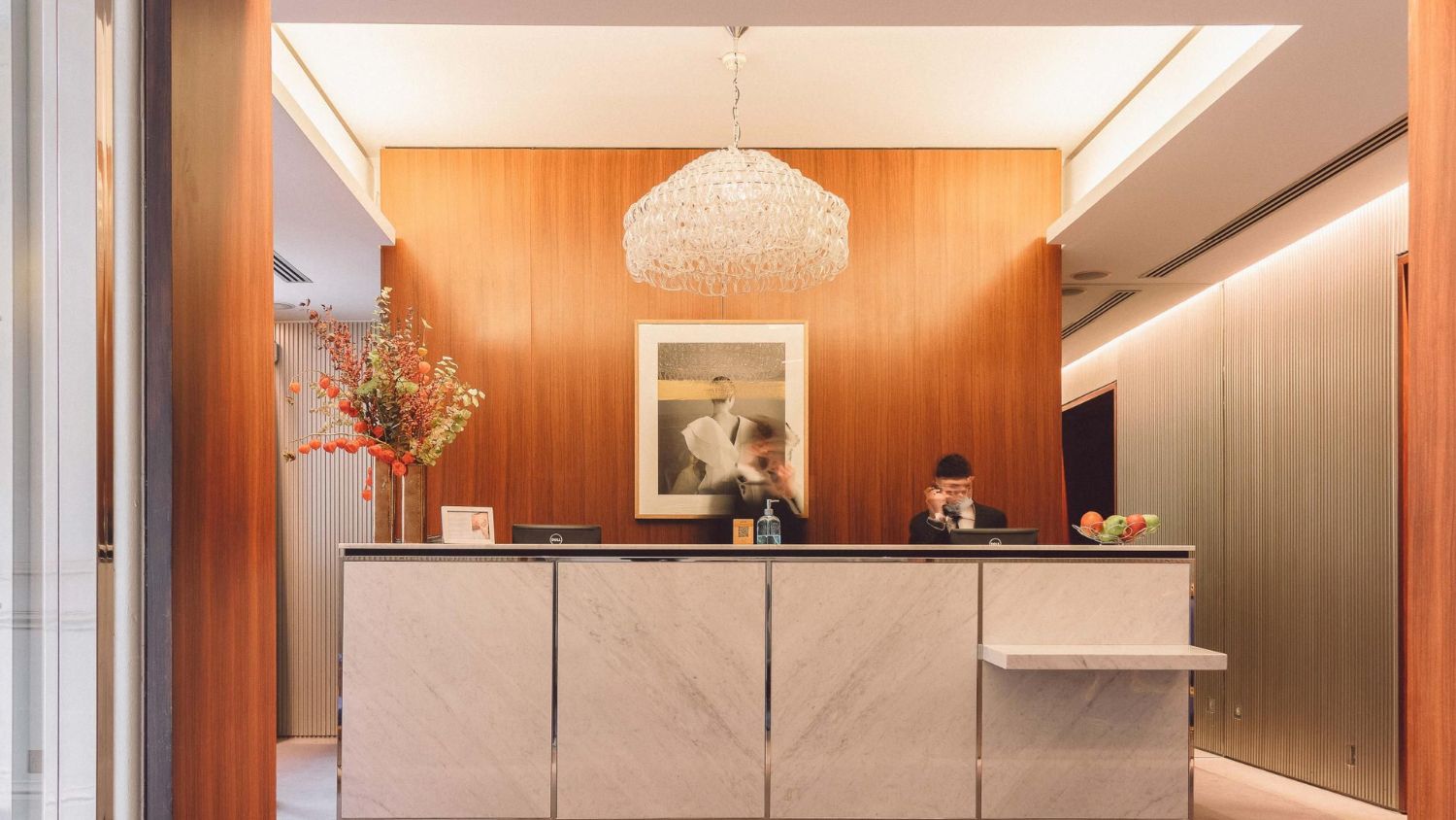Reception desk at Hotel de Sers with marble accents and modern chandelier lighting.