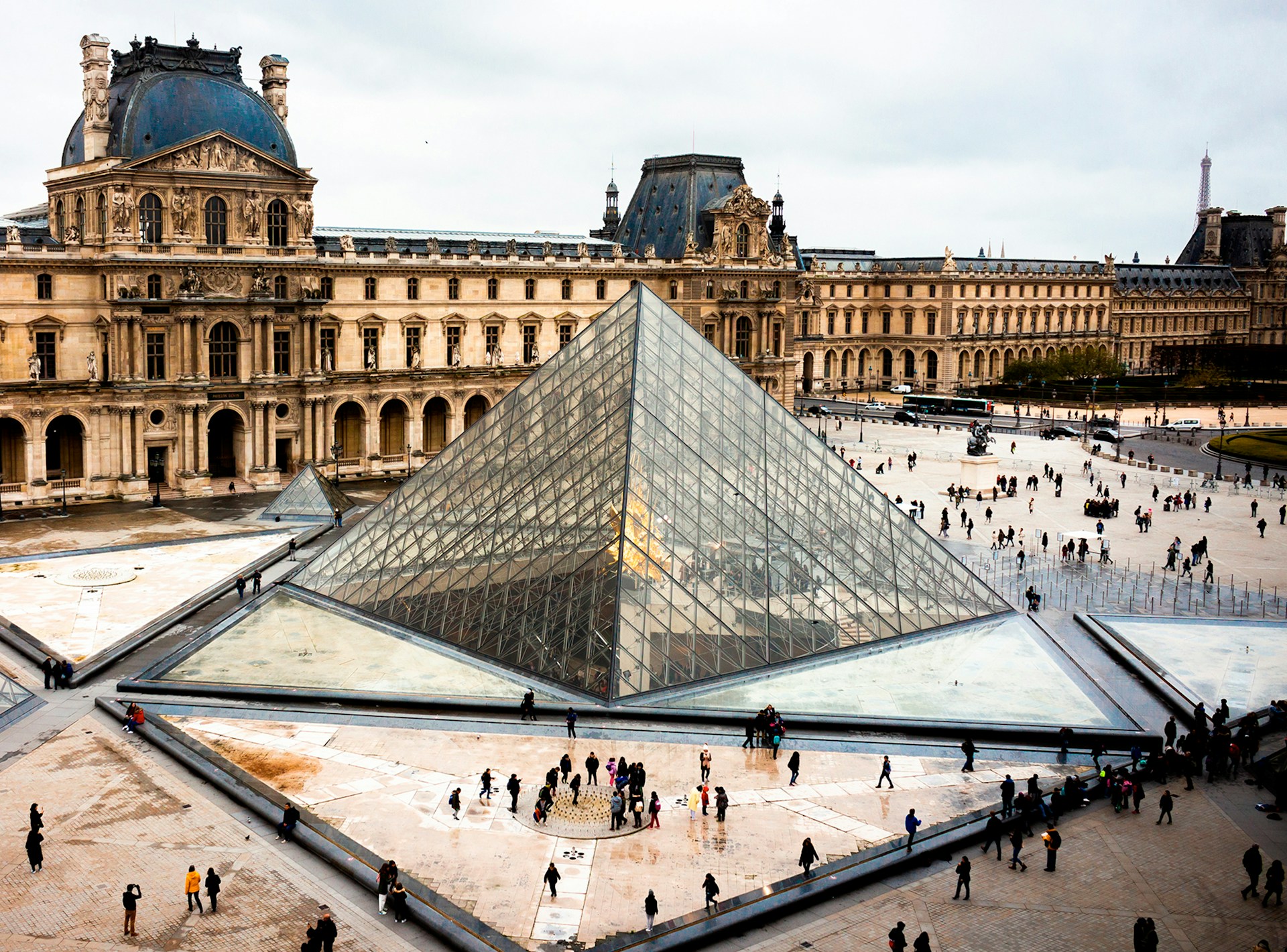 View of the Louvre Pyramid in Paris with visitors in the courtyard, a must-see stop for solo travellers discovering the City of Light.