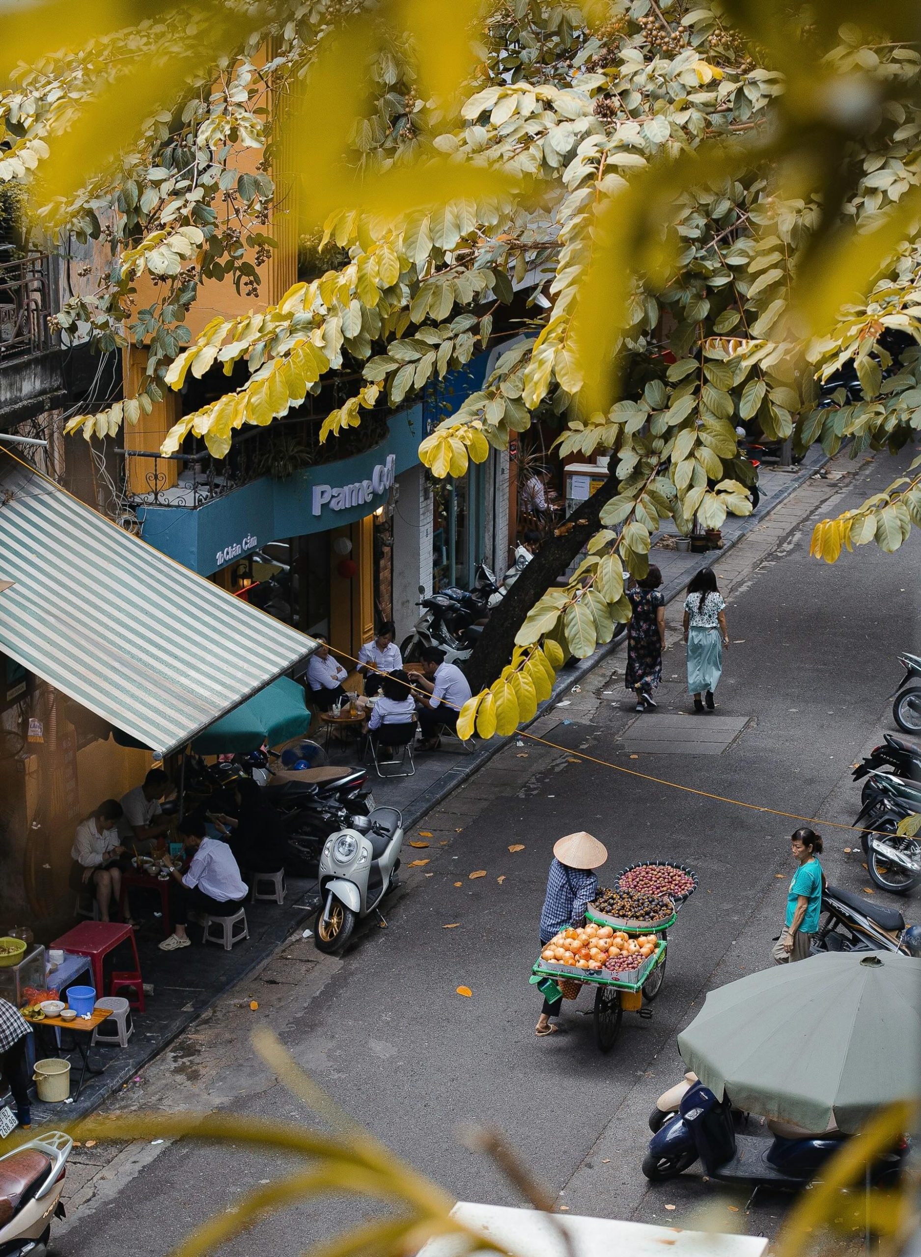 Street scene in Hanoi, Vietnam, showing locals enjoying traditional dishes and authentic Vietnamese coffee in the city’s historic streets with Chinese and French architectural influences.