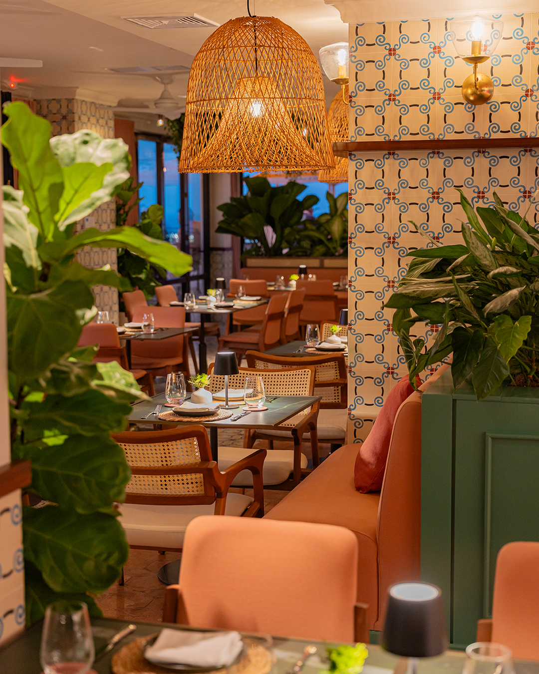 Ammi Sky Bar interior with lush hanging plants creating natural privacy between tables, inspiring the jungle-print uniforms worn by staff.