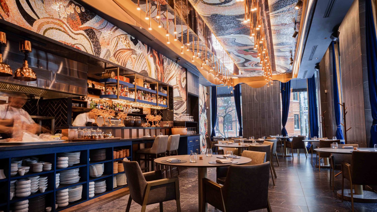 Mosaic tiles ripple across the floors and walls, catching the light like sunlight refracting off the rim of a glass, while a rich palette of coral red, creamy gold, smoky lavender and deep forest green adds depth and contrast.