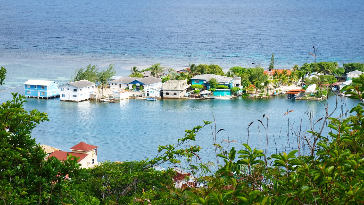 A splash of Caribbean colour. The pastel-hued stilt houses of Oak Ridge Harbour, Roatán, stand above the turquoise water—a quiet contrast to the island's busier cruise port.